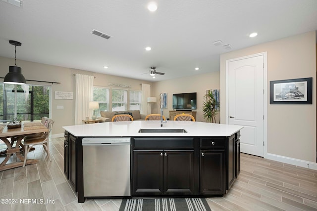 kitchen with sink, dishwasher, hanging light fixtures, light hardwood / wood-style flooring, and a center island with sink