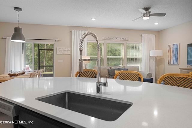 kitchen featuring sink, a textured ceiling, white dishwasher, ceiling fan, and decorative light fixtures