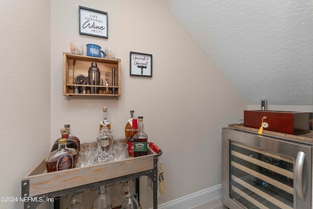 bar with wine cooler, lofted ceiling, and a textured ceiling