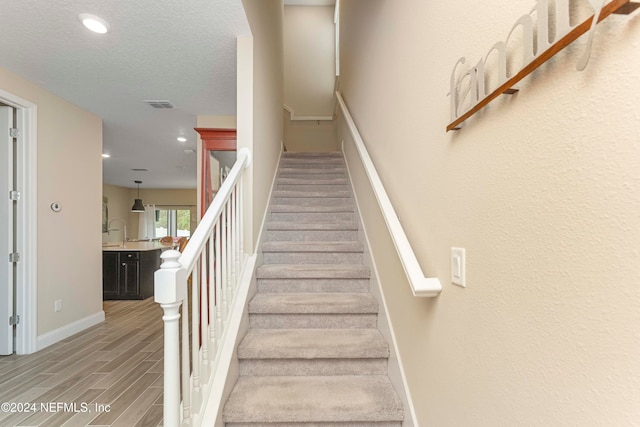 staircase featuring hardwood / wood-style flooring and a textured ceiling