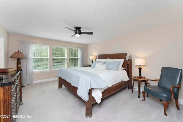 bedroom with a textured ceiling, light colored carpet, and ceiling fan