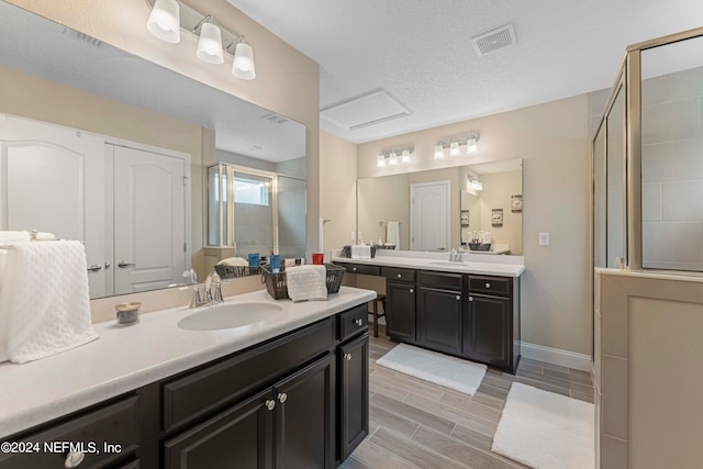 bathroom with vanity, a textured ceiling, and a shower with shower door