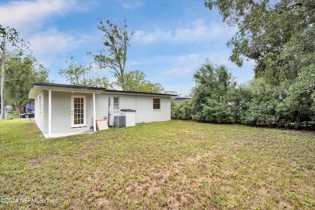 rear view of property featuring a yard and cooling unit