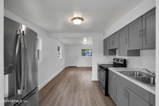 kitchen featuring appliances with stainless steel finishes, light hardwood / wood-style flooring, gray cabinetry, and sink