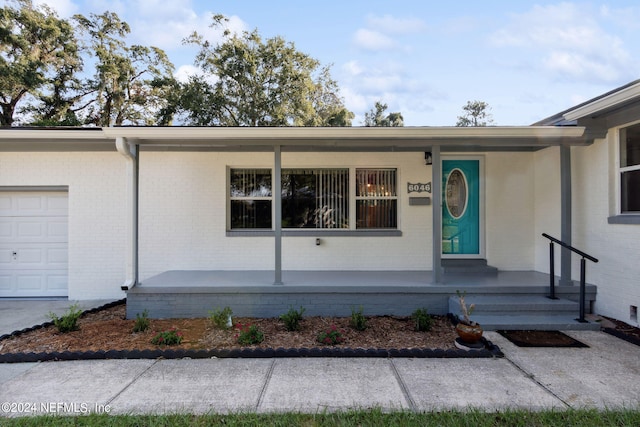 doorway to property with covered porch and a garage