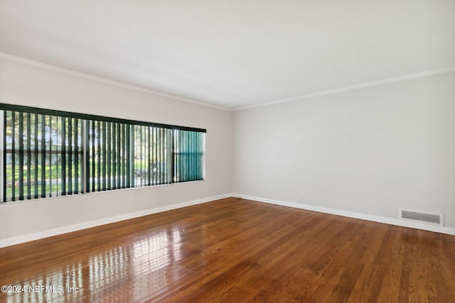 empty room with crown molding and wood-type flooring