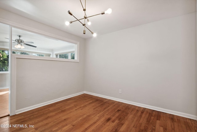 spare room featuring hardwood / wood-style flooring and a chandelier