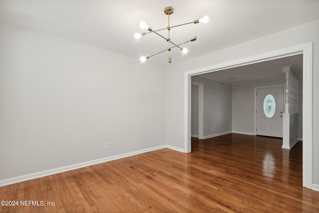 unfurnished room featuring a notable chandelier and dark hardwood / wood-style floors