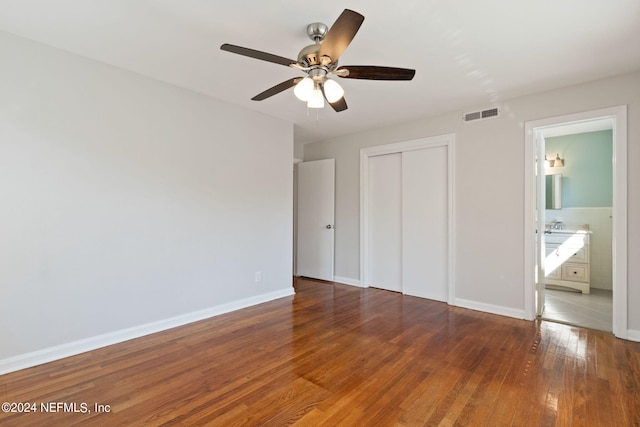 unfurnished bedroom with ensuite bathroom, dark hardwood / wood-style floors, a closet, and ceiling fan