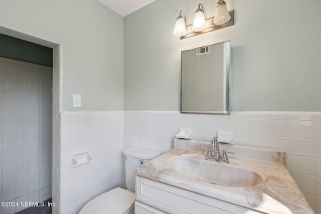 bathroom featuring tile walls, vanity, and toilet