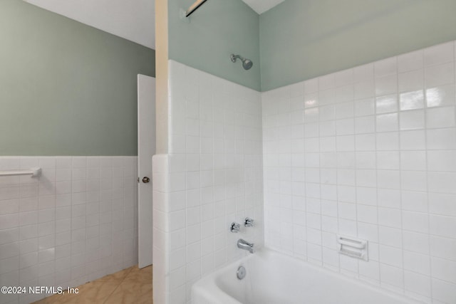 bathroom with tile patterned floors, tiled shower / bath combo, and tile walls