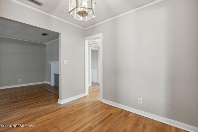 empty room with ornamental molding, hardwood / wood-style flooring, and a chandelier