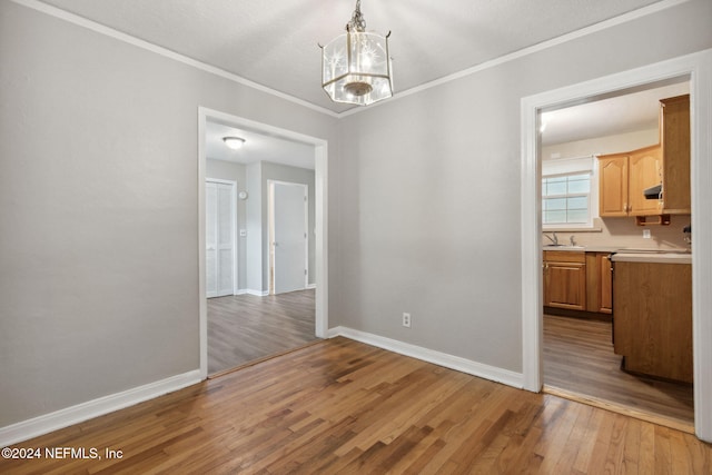 unfurnished dining area featuring light hardwood / wood-style floors, a notable chandelier, ornamental molding, and sink