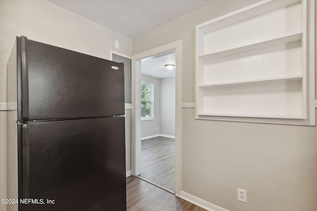 kitchen featuring wood-type flooring and black fridge