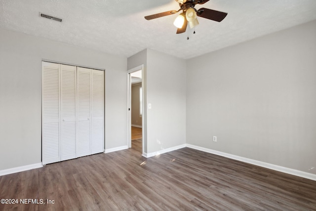 unfurnished bedroom with a closet, a textured ceiling, ceiling fan, and dark hardwood / wood-style flooring