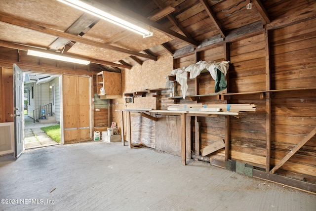 interior space featuring lofted ceiling, wooden walls, and a workshop area