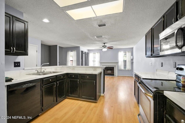 kitchen with kitchen peninsula, a textured ceiling, sink, light hardwood / wood-style floors, and stainless steel appliances