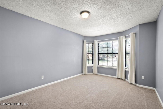 spare room featuring light carpet and a textured ceiling