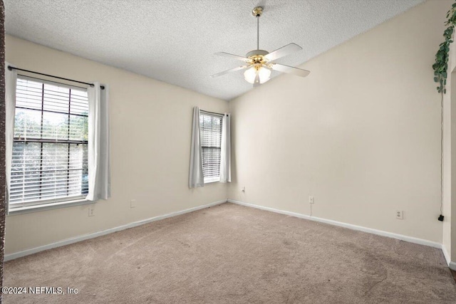 carpeted spare room featuring a textured ceiling, ceiling fan, and a wealth of natural light