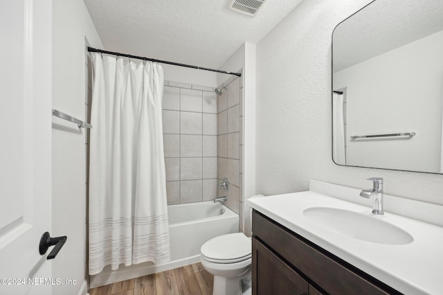 full bathroom featuring toilet, shower / tub combo, hardwood / wood-style floors, vanity, and a textured ceiling