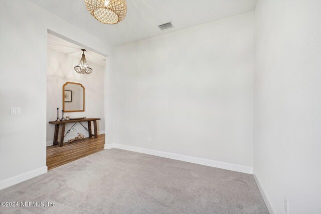 spare room featuring carpet flooring and an inviting chandelier