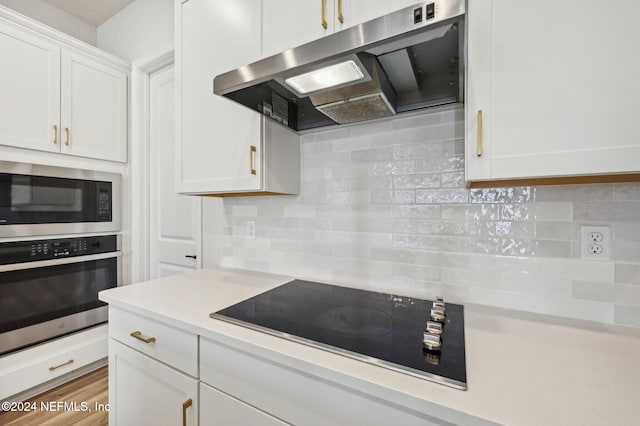 kitchen featuring hardwood / wood-style floors, decorative backsplash, white cabinets, and stainless steel appliances