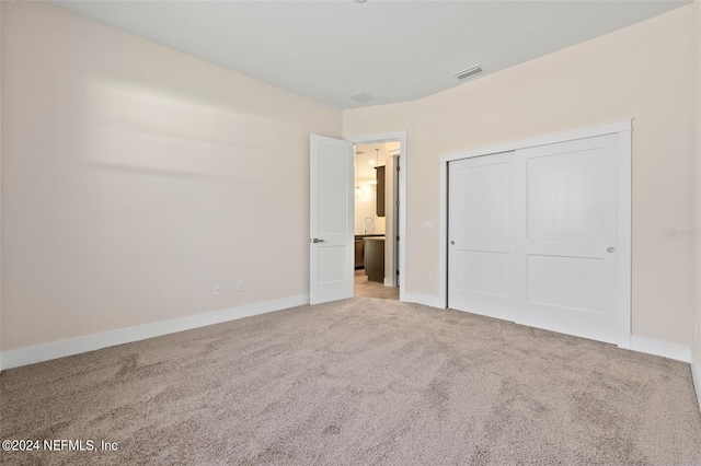 unfurnished bedroom featuring light carpet and a closet