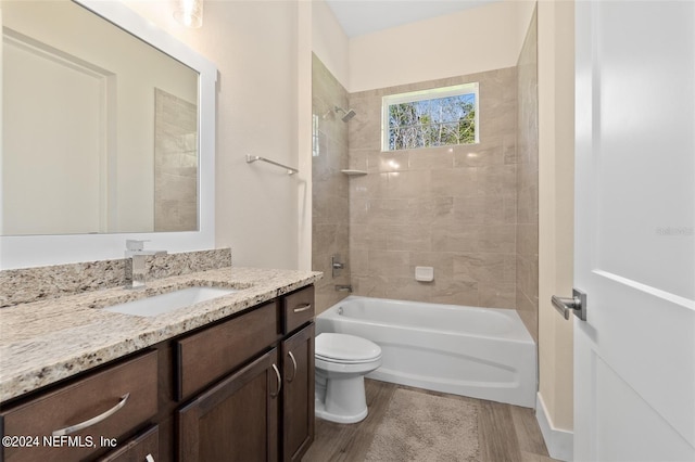 full bathroom featuring tiled shower / bath, vanity, hardwood / wood-style flooring, and toilet