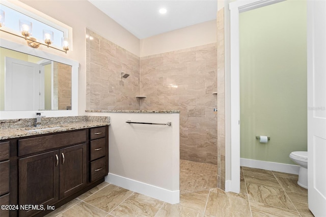 bathroom with vanity, toilet, and a tile shower