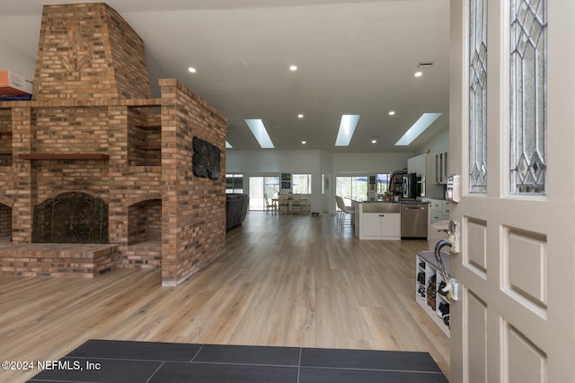 living room featuring vaulted ceiling with skylight and light wood-type flooring