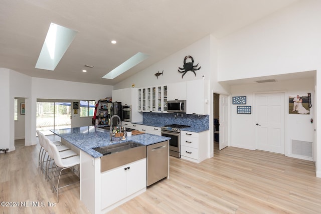 kitchen featuring light hardwood / wood-style flooring, appliances with stainless steel finishes, a skylight, and an island with sink