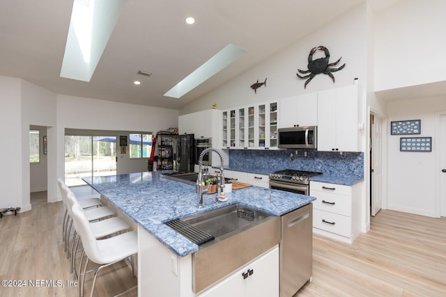 kitchen featuring stainless steel appliances, a skylight, and a kitchen island with sink