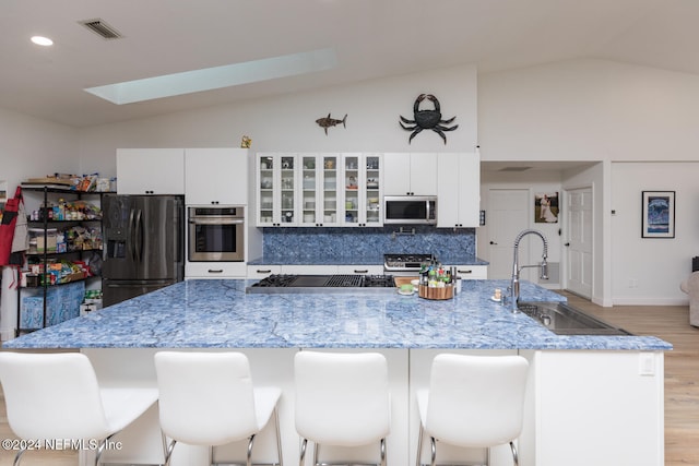 kitchen featuring appliances with stainless steel finishes, light hardwood / wood-style flooring, vaulted ceiling with skylight, and sink