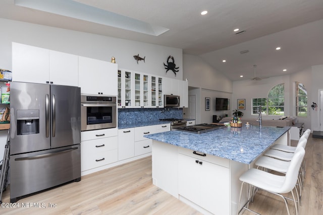 kitchen featuring stainless steel appliances, a kitchen island with sink, light wood-type flooring, and a kitchen breakfast bar