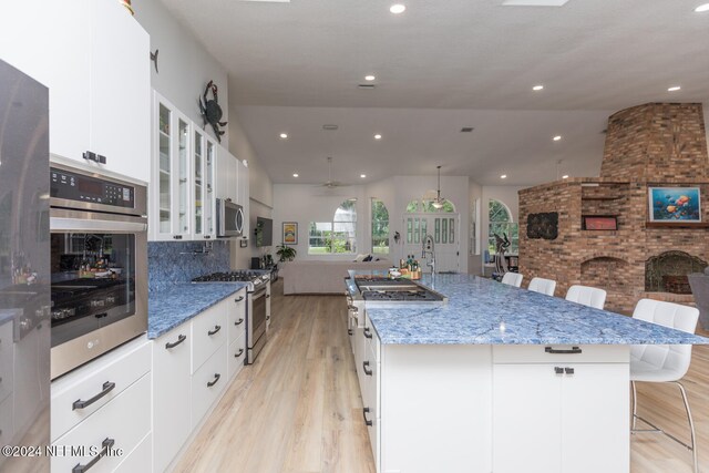 kitchen with a spacious island, a breakfast bar, white cabinets, and stainless steel appliances