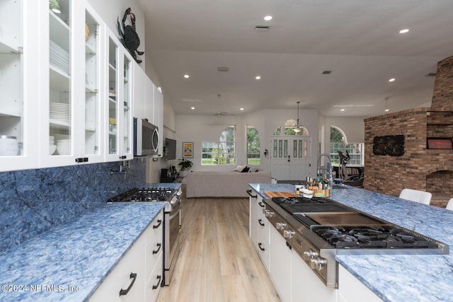 kitchen featuring light hardwood / wood-style floors, decorative backsplash, white cabinetry, and stainless steel appliances