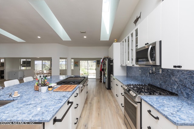 kitchen with appliances with stainless steel finishes, a skylight, a kitchen breakfast bar, and white cabinets