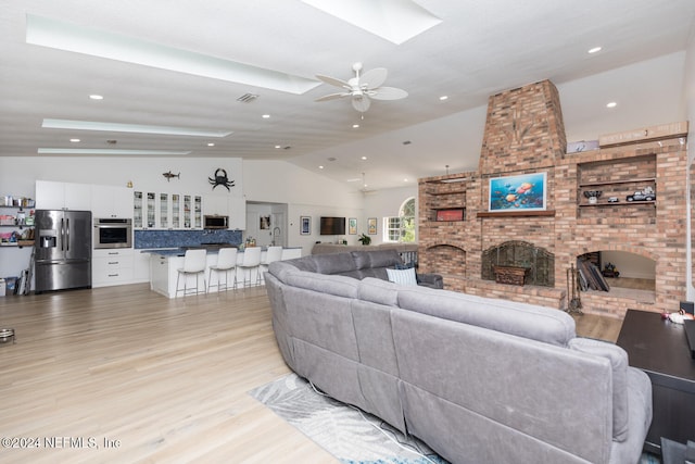 living room with light hardwood / wood-style floors, lofted ceiling, a fireplace, and ceiling fan