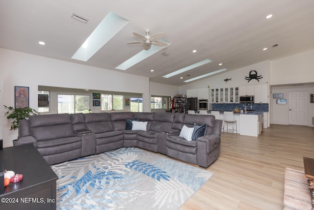 living room with sink, vaulted ceiling, light hardwood / wood-style flooring, and ceiling fan