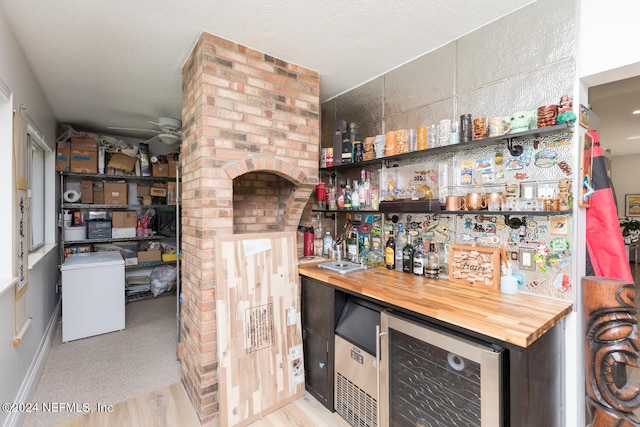 interior space featuring butcher block counters, wine cooler, light wood-type flooring, a textured ceiling, and ceiling fan