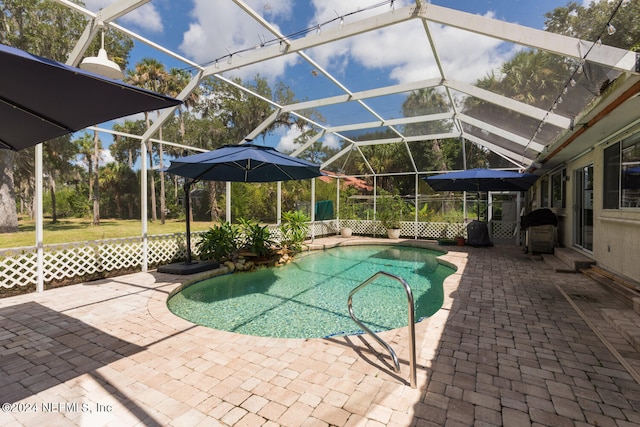 view of pool featuring a patio area, glass enclosure, and a grill