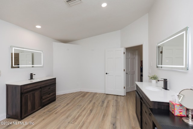 bathroom with vanity, high vaulted ceiling, a textured ceiling, and hardwood / wood-style floors