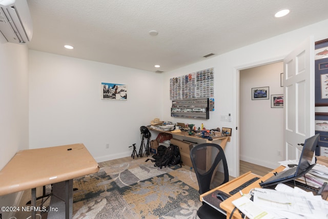 office featuring a textured ceiling, a wall mounted air conditioner, and wood-type flooring