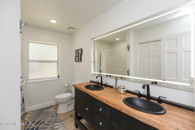 bathroom featuring vanity, hardwood / wood-style flooring, toilet, and walk in shower