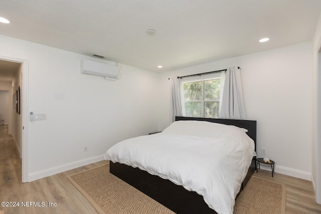 bedroom featuring light hardwood / wood-style floors and a wall mounted air conditioner