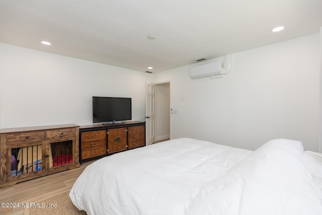 bedroom with an AC wall unit and light hardwood / wood-style flooring