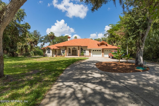 mediterranean / spanish-style home with a front yard and a garage