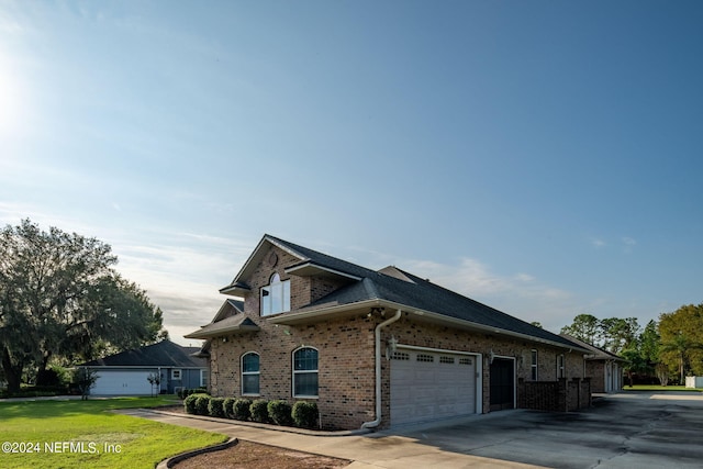 view of side of property featuring a garage and a lawn