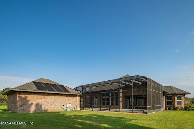 rear view of house with a yard and glass enclosure