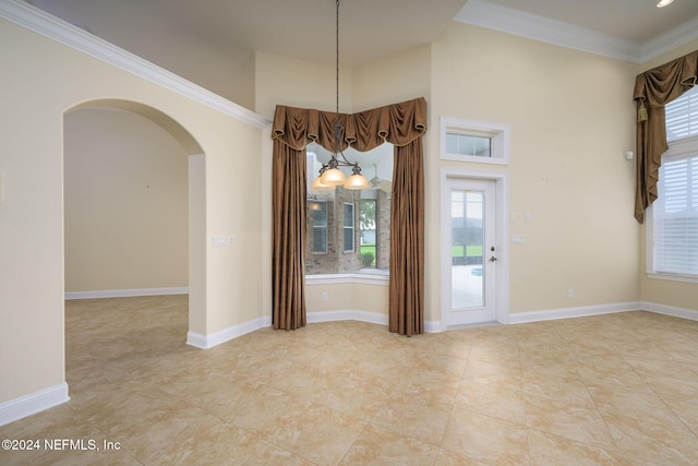 spare room with crown molding and an inviting chandelier